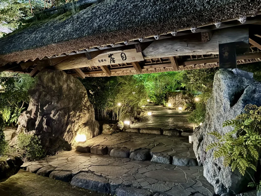 茅葺き屋根の門をくぐると、巨石と竹に囲まれた石畳のアプローチが続く