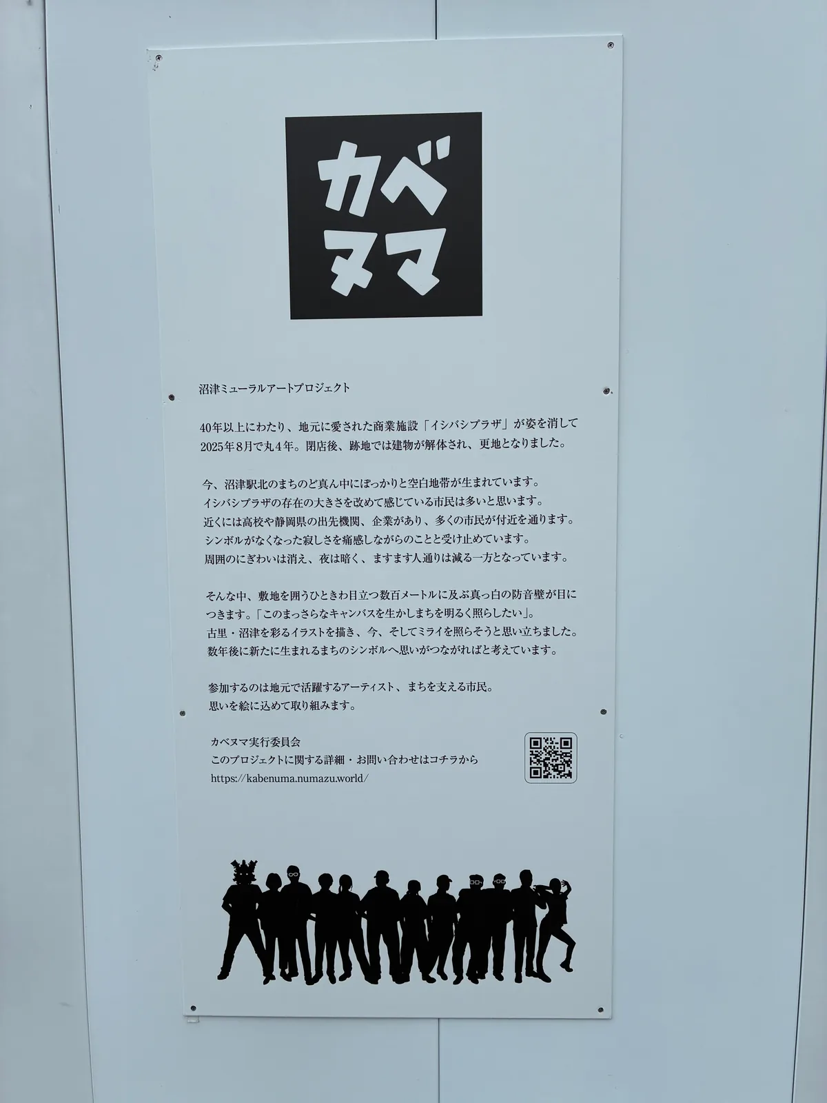 仮囲いに貼られたカベヌマの説明パネル。黒地に白い「カベヌマ」のロゴと、沼津ミューラルアートプロジェクトの趣旨文、参加者のシルエット