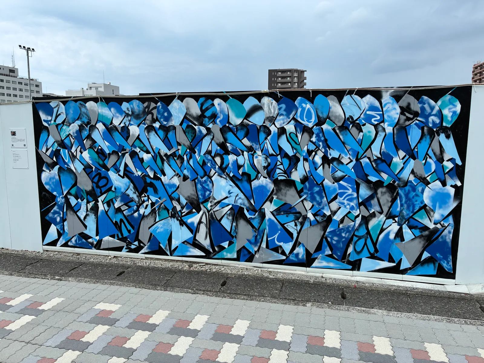 黒地に青、水色、グレーのハート形が隙間なく重なり合う壁画「前進する身体」