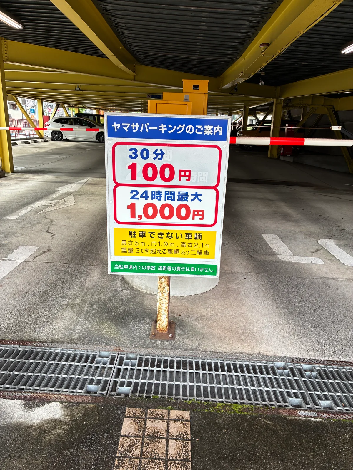 ヤマサパーキングの場内の案内看板。30分100円、24時間最大1,000円。駐車できない車両は長さ5m・幅1.9m・高さ2.1m・重量2tを超える車両と二輪車