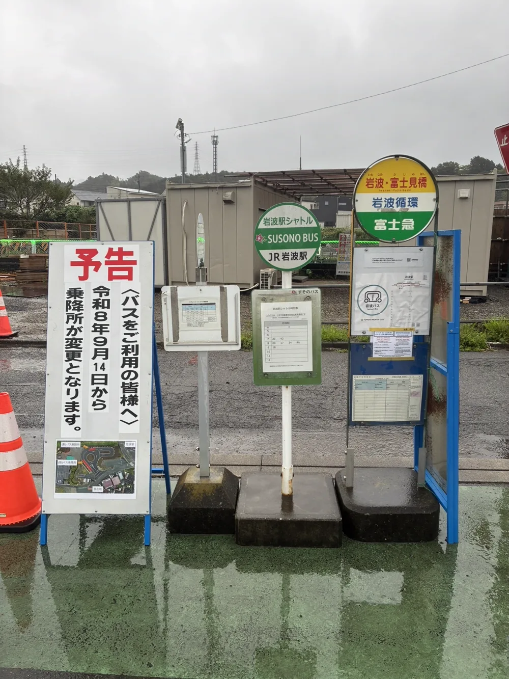移設前の岩波駅前の乗降所。予告看板の右に、すそのバス「岩波駅シャトル」と富士急「岩波・富士見橋」のバス停ポールが並んで立っている