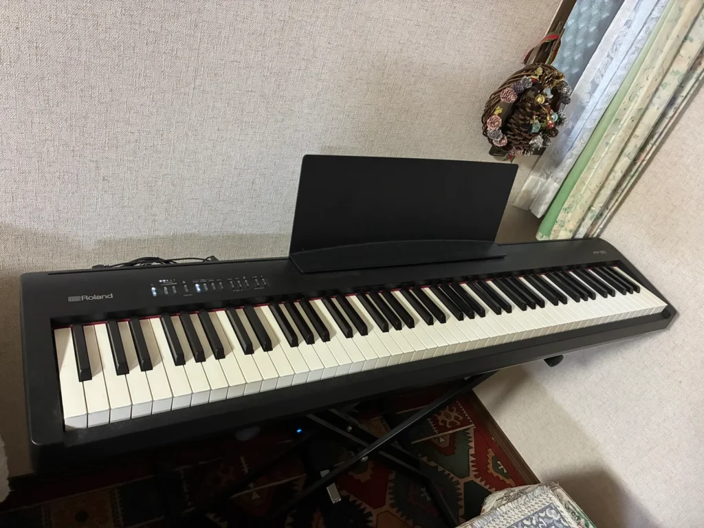 黒いRoland FP-30を斜め上から見たところ。88鍵の鍵盤と譜面台、左奥に操作ボタンが並ぶ