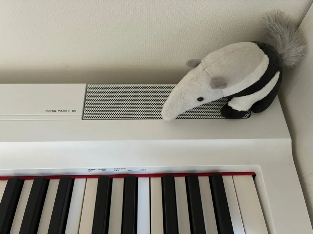 P-125本体の「DIGITAL PIANO P-125」の表示。右のスピーカーの上にアリクイのぬいぐるみが乗っている